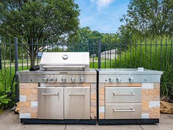 Two stone BBQs with a grill on top and a smaller one on the right.